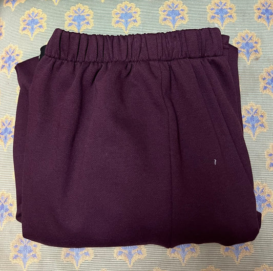 Adaptive open-back burgundy sweatpants made from soft cotton fleece, displayed folded on a patterned background.